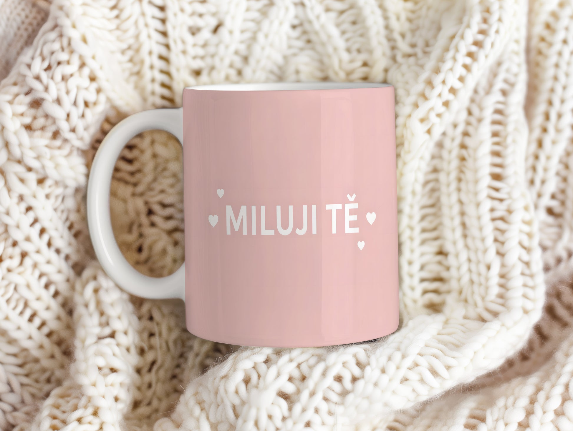 Růžový hrnek s nápisem MILUJI TĚ a malými srdíčky.