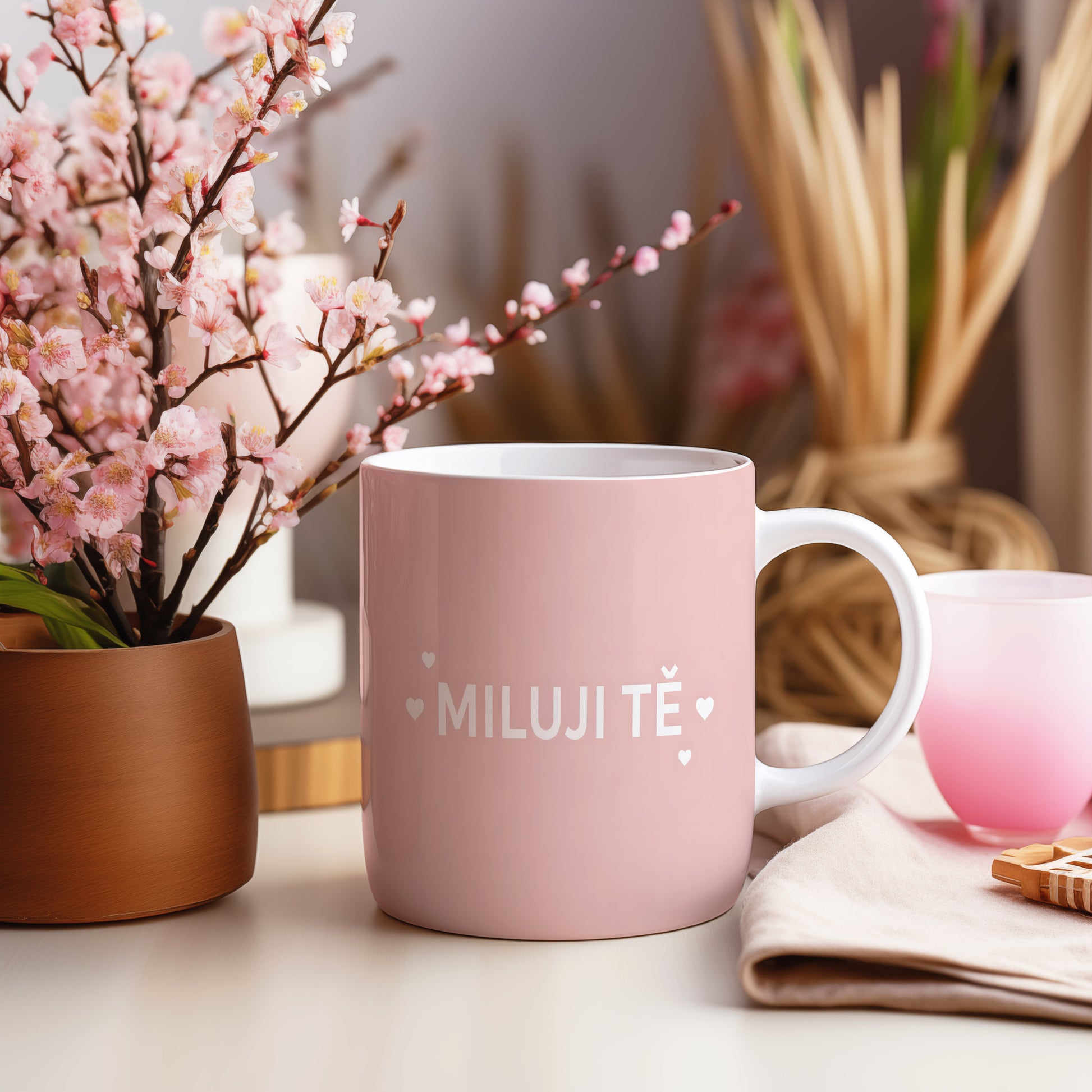 Růžový hrnek s nápisem MILUJI TĚ a malými srdíčky.