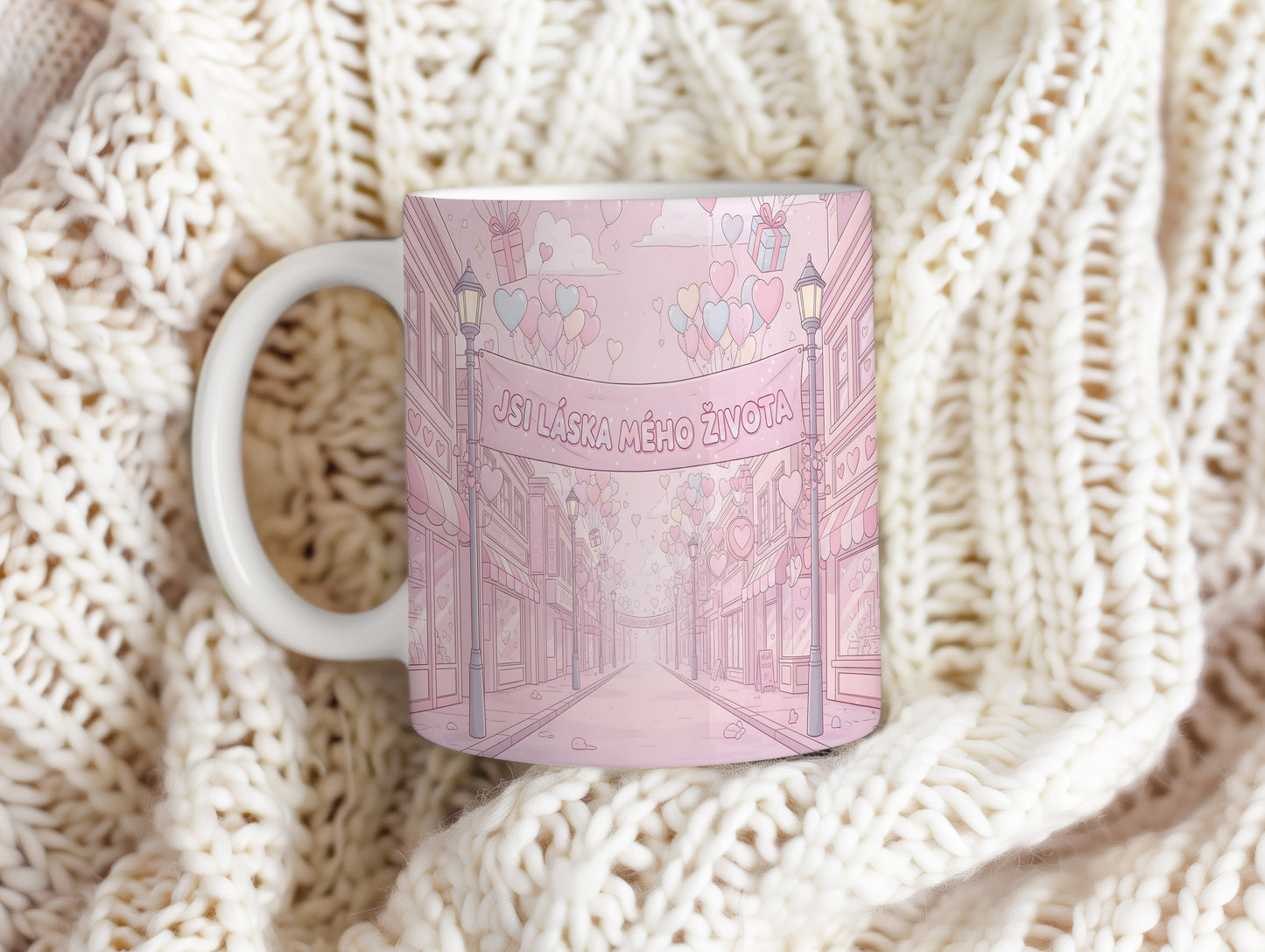 Růžový hrnek s romantickým motivem srdcí a balónků.