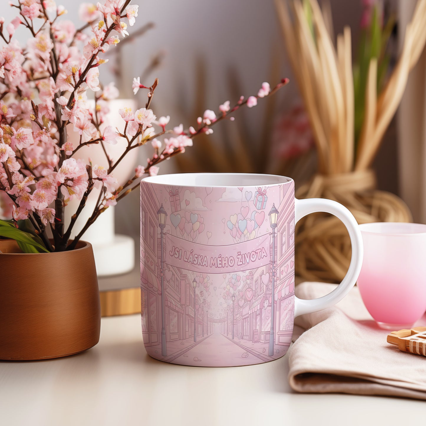 Růžový hrnek s romantickým motivem srdcí a balónků.