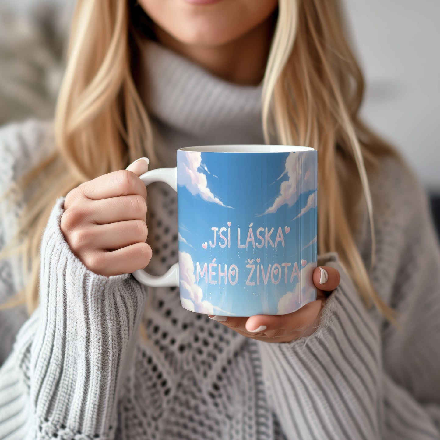 Hrnek s nápisem JSI LÁSKA MÉHO ŽIVOTA na modré obloze s oblaky a srdíčky.