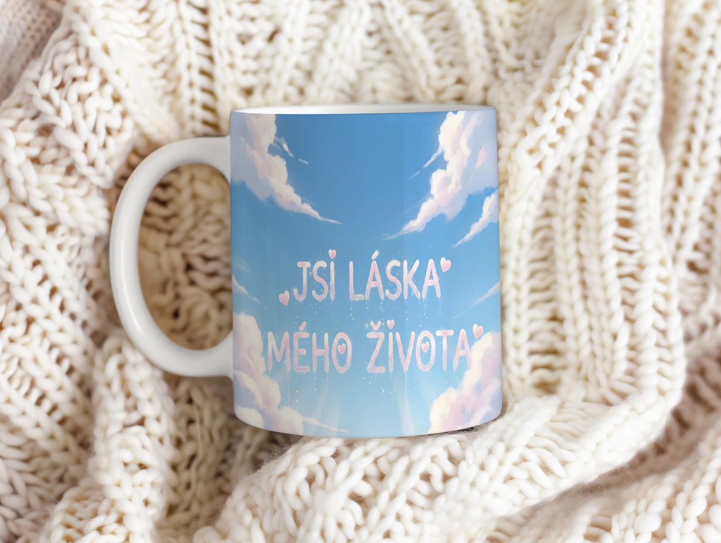 Hrnek s nápisem JSI LÁSKA MÉHO ŽIVOTA na modré obloze s oblaky a srdíčky.