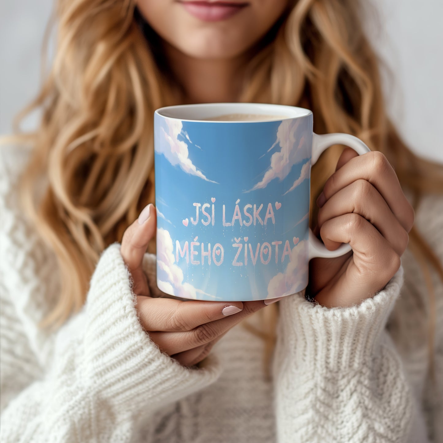 Hrnek s nápisem JSI LÁSKA MÉHO ŽIVOTA na modré obloze s oblaky a srdíčky.