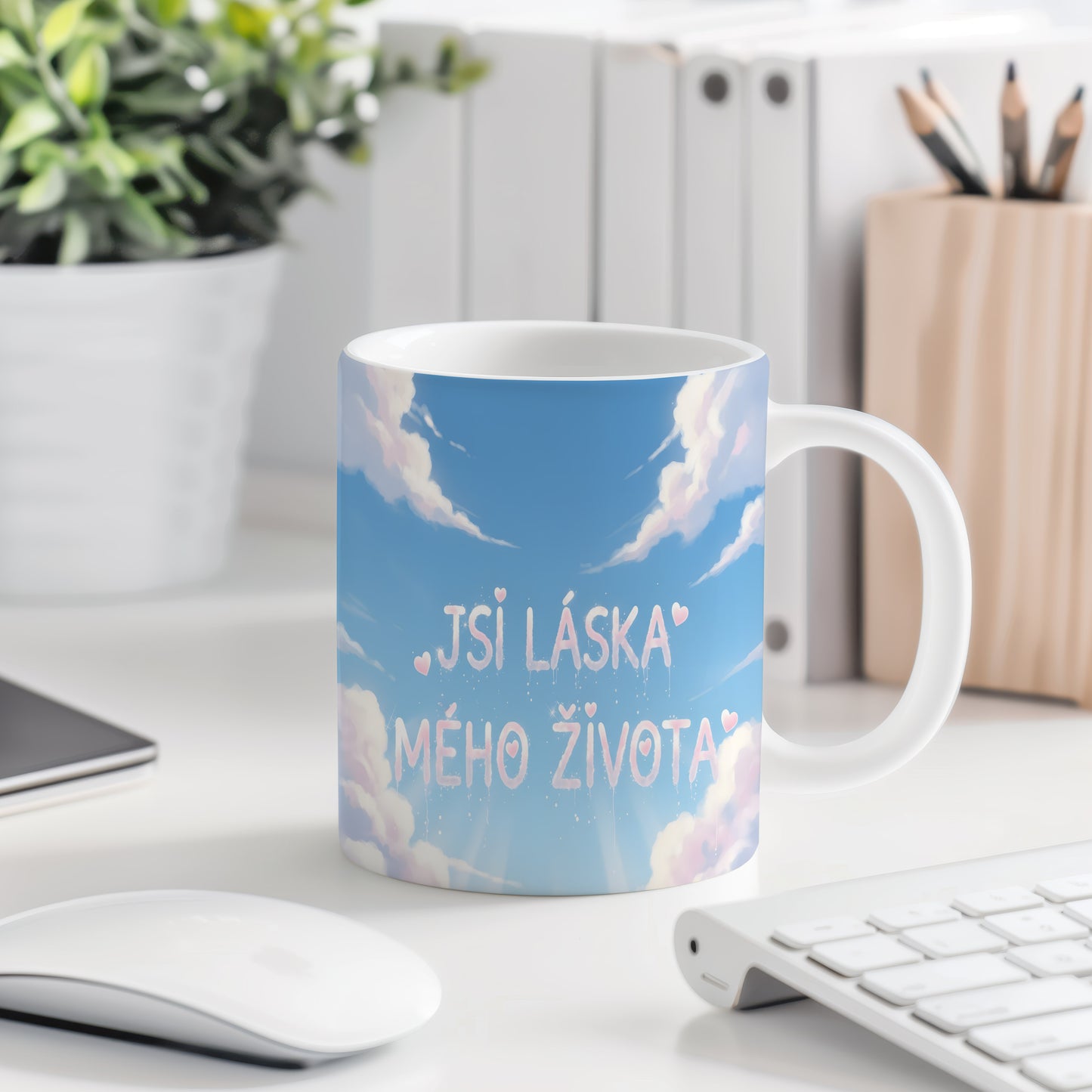 Hrnek s nápisem JSI LÁSKA MÉHO ŽIVOTA na modré obloze s oblaky a srdíčky.